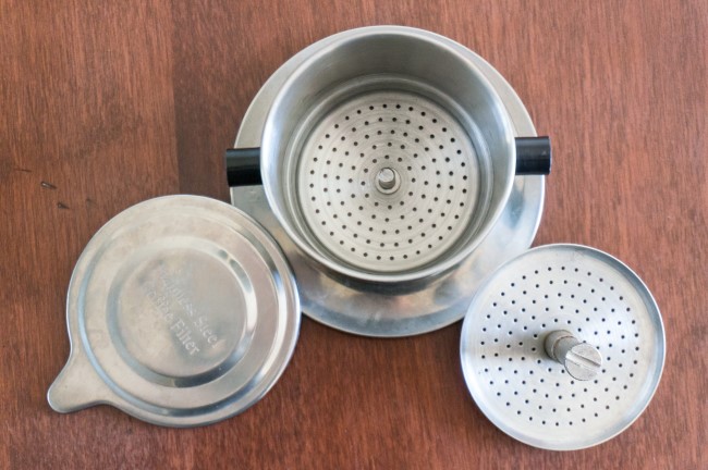 How to Brew Vietnamese Iced Coffee June 9, 2014 by Michael Allen Smith Vietnamese style iced coffee (ca phe sua da or cà phê sữa đá) is super easy to make and all you need is a stainless steel filter that costs around $7 USD online. If you live in a city with a Vietnamese grocery store, you will likely find them even cheaper. Vietnamese coffee can be served hot, but for this tutorial we are going to brew an iced coffee that is both strong and sweet. Although it is traditional to use dark roasted coffee for this drink, I discovered it is perfectly fine to use a medium roast. However, light roasted coffees should be avoid as they tend to be overpowered by the sweetness of the condensed milk. What You’ll Need Vietnamese Coffee Filter Ground coffee Sweetened Condensed Milk Spoon Glass or mug Ice Vietnamese Coffee Brewer Vietnamese Coffee Filter Set